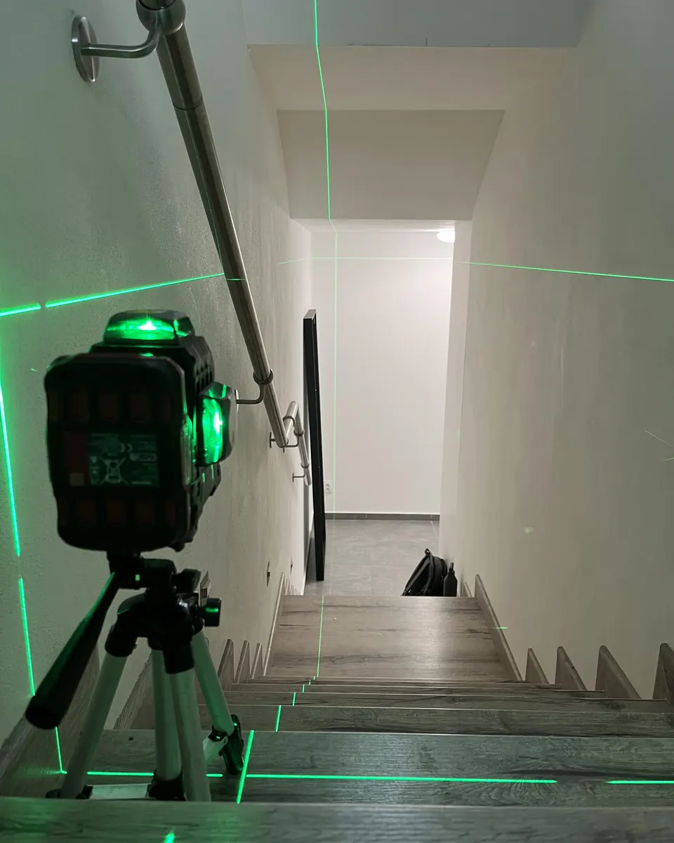 Křížový laser na stativu vyměřuje schodiště při rekonstrukci rodinného domu u Prahy